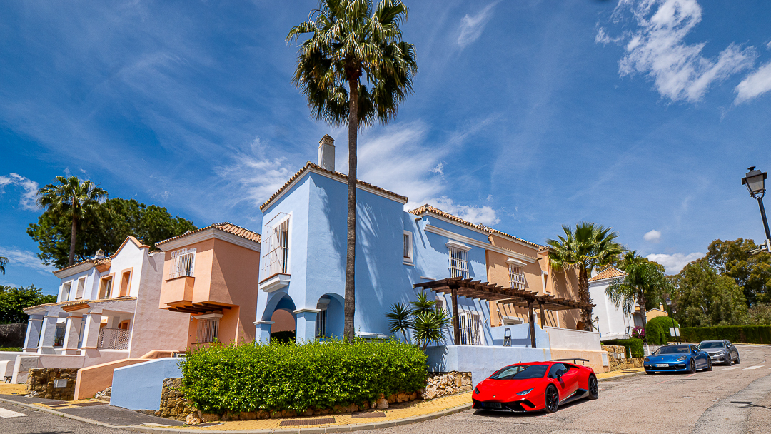 Luxury villa exterior with blue facade and sports cars