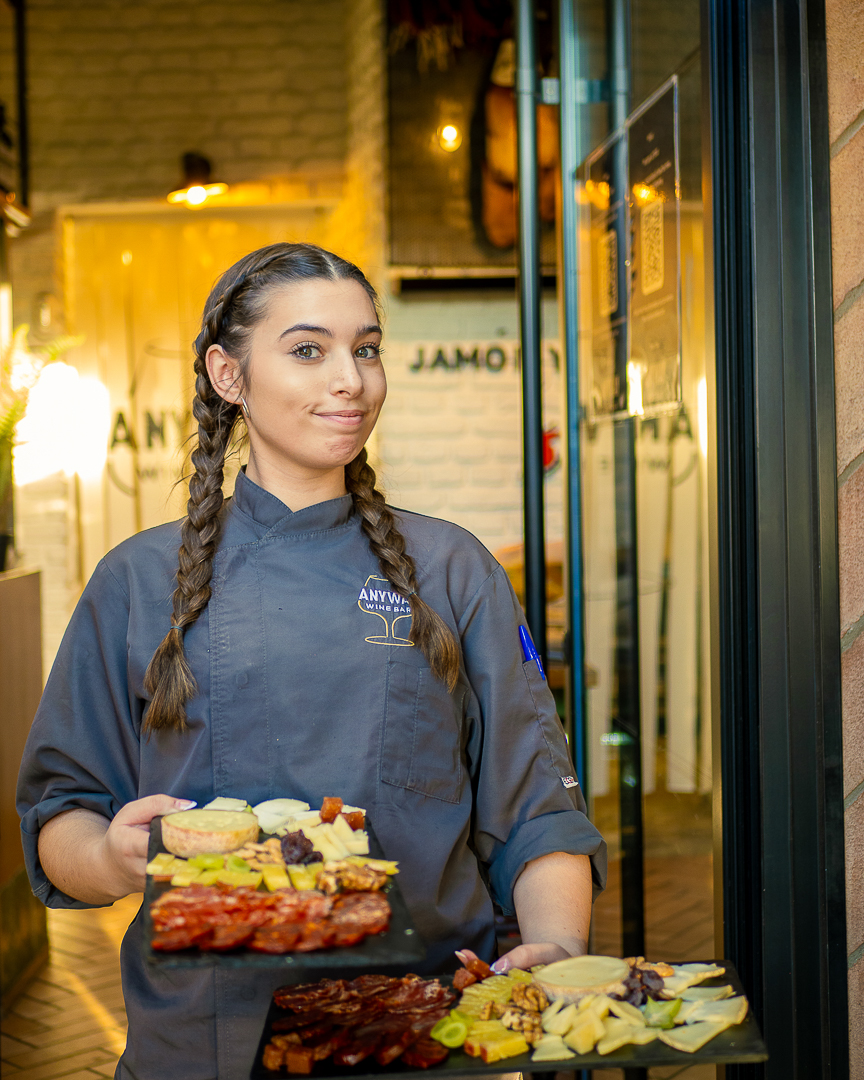 Restaurant team member presenting curated platters outside Anyway Wine Bar