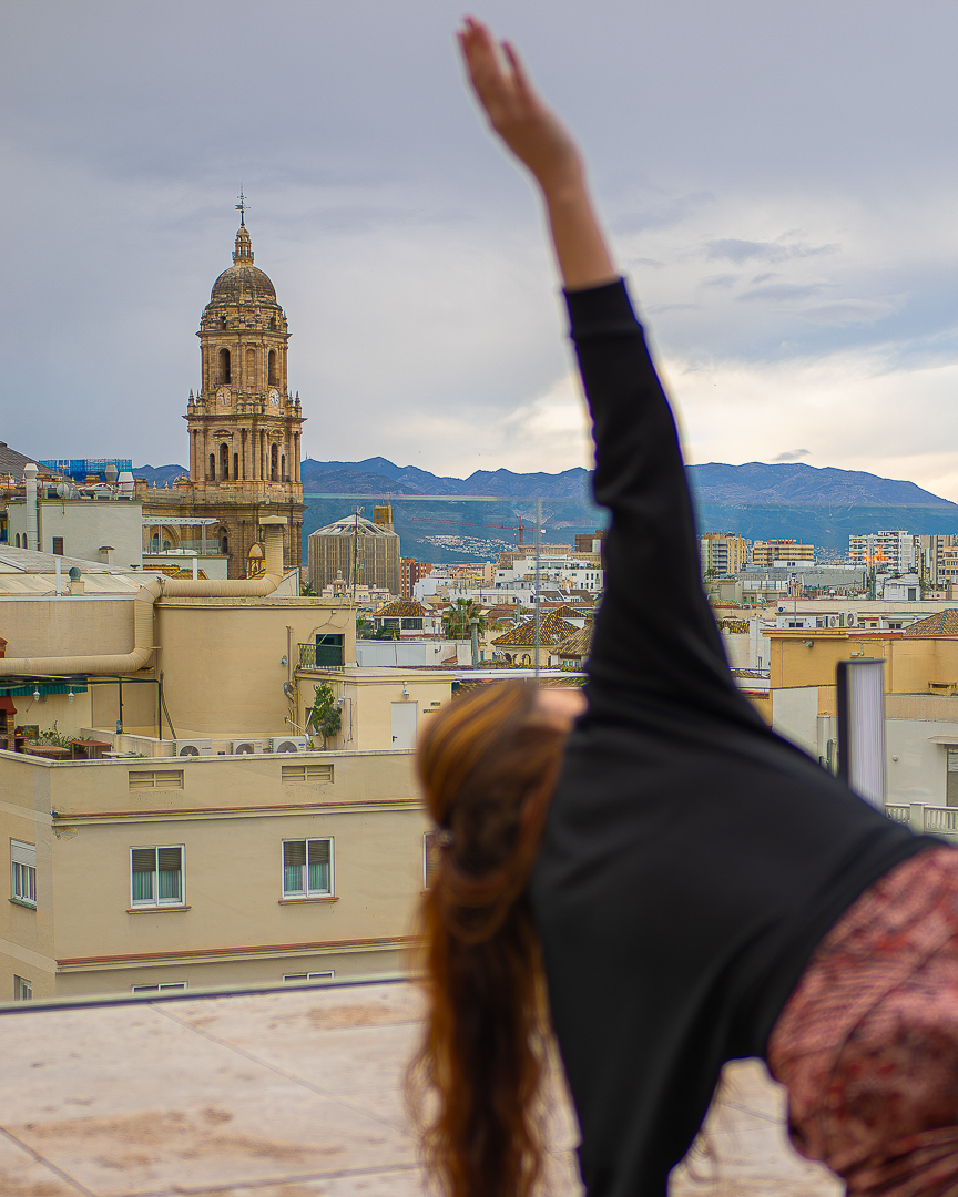 Rooftop yoga stretch overlooking Málaga cathedral